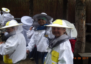 Dzieci w ubraniach pszczelarskich.